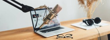 Geniş görüntü. Yayın stüdyosu, iç mekan. Podcast için ev yapımı oda. Ses mikrofonu, tahta masadaki dizüstü bilgisayar.