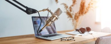 Stüdyo podcast iç dizisi. İçeriden yayın yapın. Podcaster için ev yapımı oda. Ses mikrofonu, dizüstü bilgisayar ve lamba ahşap masada. Geniş resim