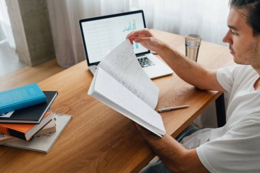 Lise öğrencisi dijital öğrenme yaparken üniversiteyi geçmek için hazırlanıyor. Bilgisayarı kullanarak uzaktan öğrenirken evde dalgın bir adam