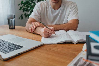 Üniversiteye geçmek için çevrimiçi öğrenim görürken kampüste üniversite öğrencisi. Düşünceli adam evde dizüstü bilgisayar kullanıyor.