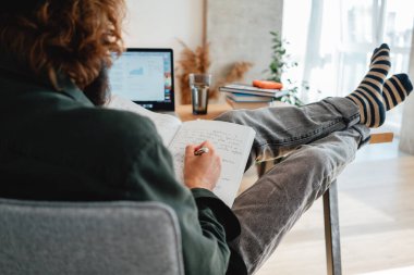 Yetişkin sakallı öğrenci çalışırken online sınavı geçmek için hazırlan. Üniversite öğrencisi Laptop kullanarak kampüste ders çalışıyor ve notlar alıyor.