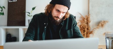 Sakallı öğrenci dizüstü bilgisayarla online sınavı geçmek için hazırlan. Üniversitede ders çalışırken not alan yetişkin bir adam. Geniş resim