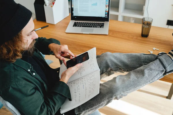 Studente Barbuto Siede Con Piedi Sulla Scrivania Mentre Studia Online Foto Stock