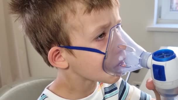 Metoda stosowana jest przez zaburzenia oddychania. Biały chłopiec w niebieskiej koszulce używa nebulizatora.Nebulizator stosowany jest do alergii, infekcji płuc, przeziębień, astmy oskrzelowej. Dziecko trzymające — Wideo stockowe