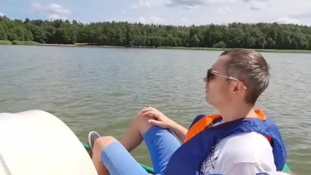 Hombre nada por el río en una bicicleta acuática, caminar al aire libre en un catamarán — Vídeo de stock