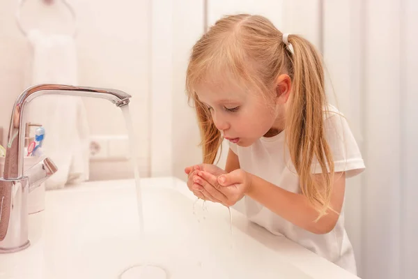 Een klein meisje dat 's morgens haar tanden spoelt. Lichte badkamer. Tandreiniging — Stockfoto