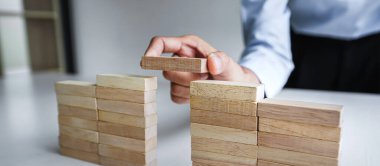 Plan and strategy in business, Risk To Make Business Growth Concept With Wooden Blocks, hand of man has piling up and stacking a wooden block. clipart