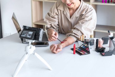 Mutlu gülümseyen zarif kadın ya da video kaydında fırçasıyla güzellik blogcusu. İnceleme ürünü kamera ekranında video blogları hakkında özel ders hazırlıyor..