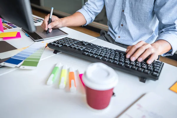 Image of male creative graphic designer working on color selection and drawing on graphics tablet at workplace with work tools and accessories in workspace.