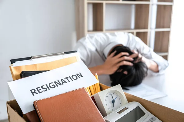 Images of packing up all his personal belongings and files into a brown cardboard box, Businessman has frustrated and stressed to resignation and signing cancellation contract letter in office.