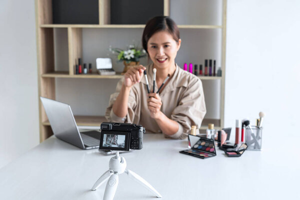 Счастливая улыбающаяся элегантная женщина блоггер показывает настоящее макияж учебник красоты косметический продукт обзора и трансляции в прямом эфире потокового видео блог в социальной сети преподавания онлайн на экране камеры.