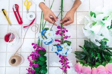 Evde suni çiçek dekorasyonu düzenleyen genç kadın çiçekçi, yapay çiçek, el işi ve el yapımı konsept düzenliyor..