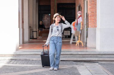 Gülümseyen kadın yolcu siyah bavul taşıyordu. Havaalanında yolcu almaya gidiyordu. Seyahat konsepti..