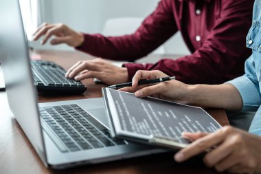 Asyalı kadın programcı, yeni bir web sitesi ya da yazılım geliştirme bürosundaki uygulama için kod yazarken, yeni proje hakkında partneriyle kod verileri tutuyor ve tartışıyordu.