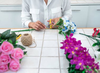 Evde suni çiçek dekorasyonu düzenleyen genç kadın çiçekçi, yapay çiçek, el işi ve el yapımı konsept düzenliyor..