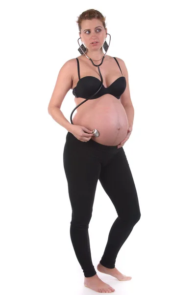 Gravid kvinna lyssna på hennes barn Stockbild
