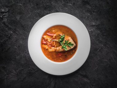 Siyah arka planda beyaz tabakta balık çorbası. Kopyalama alanı ile genel görünüm.