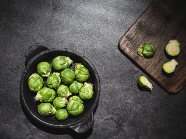 Siyah kasede taze yeşil Brüksel lahanası ve koyu arka planda kesim tahtası. Fotokopi alanı ile genel çekim.