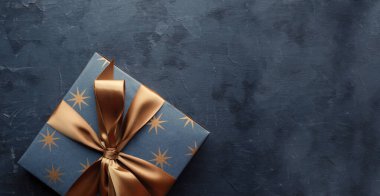 Mavi arka planda altın kurdeleli mavi hediye kutusu. Fotokopi alanı ile genel çekim.