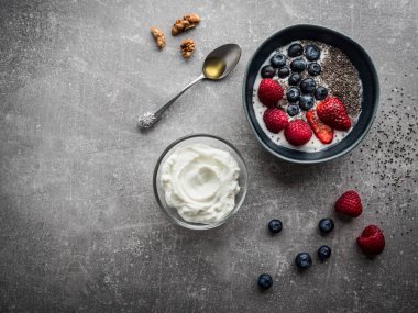 Yoğurt ve meyveli mavi kase. Ballı kaşık, ceviz ve chia çekirdeği. Fotokopi alanı ile genel çekim.