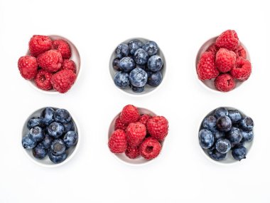 Beyaz arka planda izole edilmiş altı beyaz yaban mersini ve ahududu kasesi. Tepeden çekim.