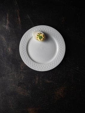 Avokado soslu haşlanmış yumurta ve beyaz tabakta taze soğan. Fotokopi alanı ile üstten çekim. Karanlık ve karamsar.