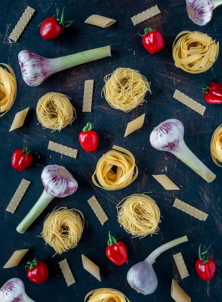 Various italian pasta with cherry tomatoes and garlic. Knolling on vintage background. Overhead shot.
