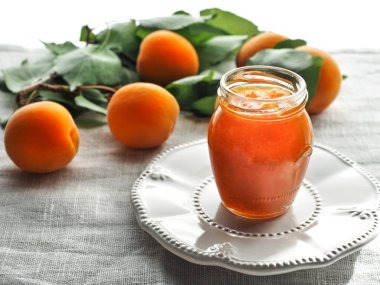 Kavanozda ev yapımı kayısı reçeli ve yeşil yapraklı taze kayısılar. Boşluğu kopyala.