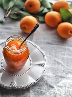 Kavanozda ev yapımı kayısı reçeli ve arka planda taze kayısılar. Boşluğu kopyala.