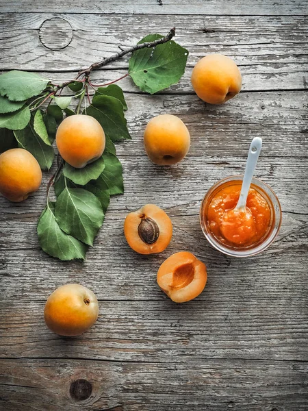 Apricot jam in jar on wooden table and fresh apricots on background. Overhead shot with copy space.