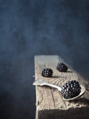 Kaşık üzerinde taze böğürtlen ve eski bir tahta parçası. Karanlık ve karamsar. Boşluğu kopyala.