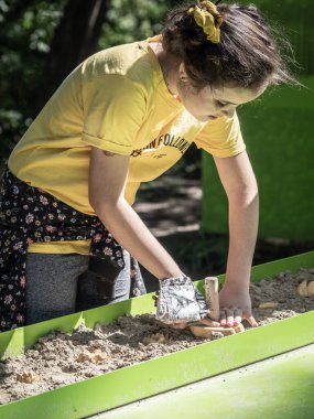 ORTH, AUSTRIA - 15 Eylül 2020: küçük beyaz kız kumda hayvan ayak izleri yapıyor. Schlossorth Ulusal Park Merkezi.