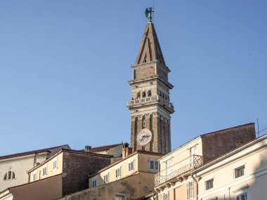 PIRAN, SLOVENIA - 15 Ağustos 2020: çatılara ve Kutsal George katedralinin kulesine bakın. Mavi gökyüzüyle güneşli bir gün.