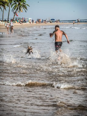 MIRISSA, SRI LANKA - 17 Mart 2019: Kafkas adam denizde köpeğiyle koşup oynuyor.
