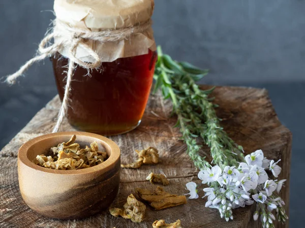 Tarro de miel, flores y cuenco de madera de gránulos de propóleos en pieza de madera. — Foto de Stock