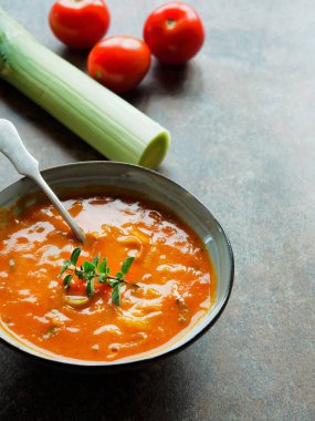 Kızarmış domateslerden yapılmış bir kase çorba ve klasik arka planda bir kaşık. Boşluğu kopyala.