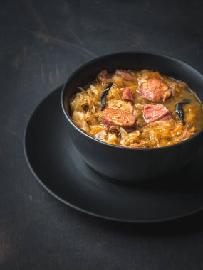 Siyah kasede lahana çorbası ve siyah arka planda tabak. Uzayı kopyala Minimalizm.