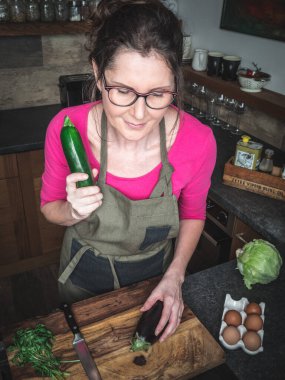 Kafkasyalı orta yaşlı kadın mutfakta sebze yemeği hazırlıyor. Sağlıklı gıda konsepti.