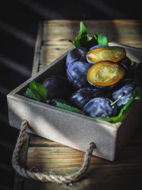 Tahta masadaki tahta kutuda dilimlenmiş erikli taze erik. Boşluğu kopyala