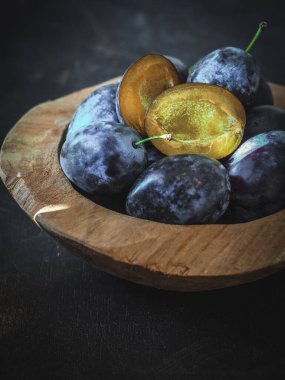 Dilimlenmiş erikli taze erik, arka planda ahşap kasede. Boşluğu kopyala.