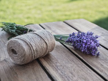Ahşap masaya bağlanmış bir demet lavanta çiçeği. Arka planda bulanık çimenler. Boşluğu kopyala. 