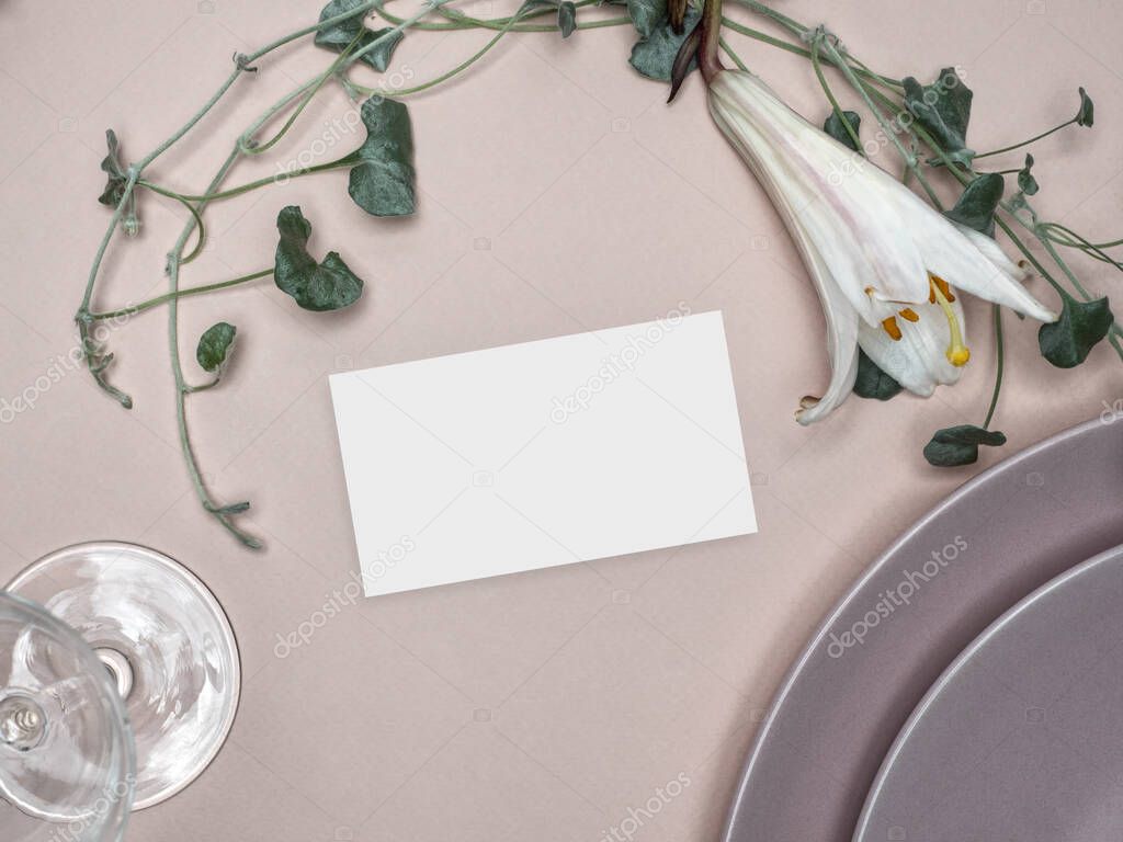 Table place mockup with green foliage and lily flower. Celebration table setting