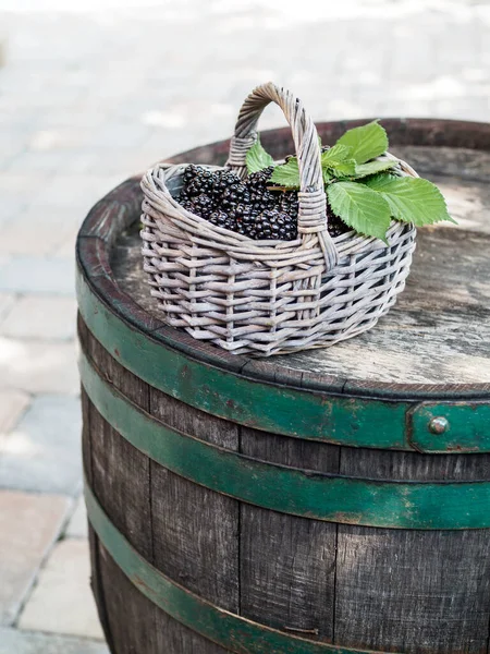 Cesto di more fresche con foglie verdi su vecchia botte di legno. — Foto Stock