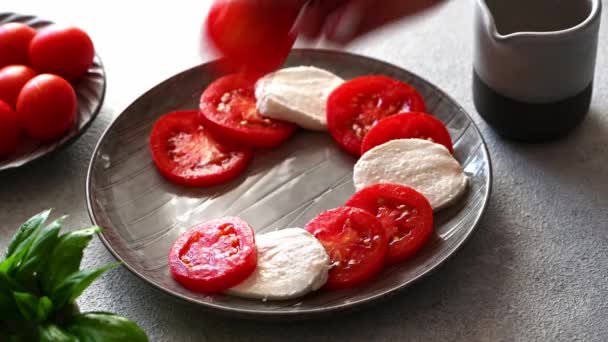 Fazendo salada caprese com mussarela, tomates e manjericão. Salada caprese clássica. Caprese italiano. Comida italiana tradicional. — Vídeo de Stock