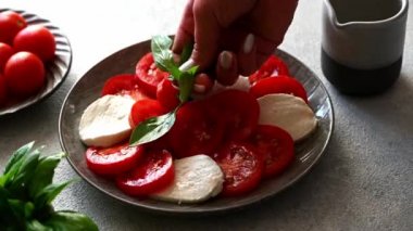 Caprese salatasına fesleğen koy. Mozzarella ve fesleğen yapraklı domates salatası. İtalyan mutfağı. Akdeniz yemeği. Organik yiyecekler. İtalyanca başlık.