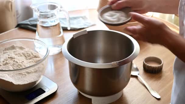 Female hands pour salt from a plate into a transparent bowl of kitchen scales. Preparing to prepare the dough. Ingredients for making homemade bread dough. Comfort food. Making dough — Stock Video