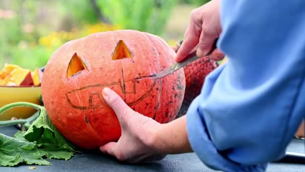 Hands carves a scary halloween pumpkin. Making pumpkin decor for Halloween. Preparation for celebration. Preparing halloween pumpkin. Jack-O-Lantern — Stock Video