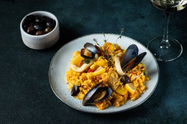 İspanya 'nın klasik yemeği, deniz ürünleri paella tabağı ve mavi arka plan manzarası. İspanyol paellası, karides, kıskaç, midye ve taze limon. İspanyol yemeği. Rahatlatıcı yemek. Deniz mahsullü pilav