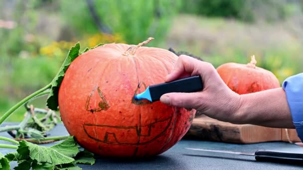 怖いハロウィーンのカボチャを作る手。ハロウィンのためのカボチャの装飾を作る。お祝いの準備だ。ハロウィーンのカボチャを準備する。ジャック・オー・ランタン — ストック動画