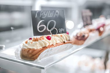 Fındıkla süslenmiş kremalı ekler, meyveler, vitrinde, yakın plan, beyaz ve parlak resim, bokeh, fotokopi alanı.